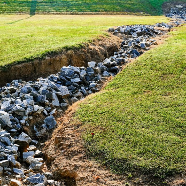 Large Granite Rocks in Drainage Ditch in Green Field